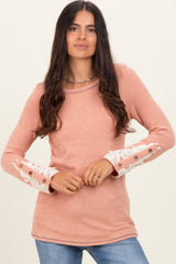 woman wearing a pink ribbed long sleeve top with lace and button details on the sleeves