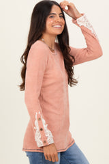 woman wearing a dusty rose ribbed long sleeve top with lace detail on the sleeves and button accents