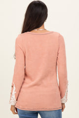 woman wearing a pink ribbed long sleeve top with lace detail on the sleeves, view of the back