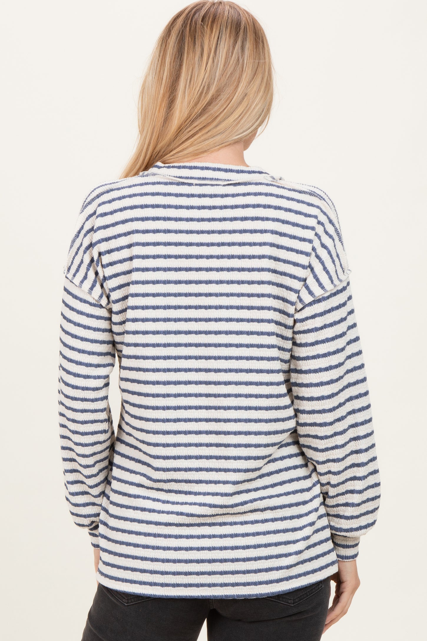 woman wearing a cream and navy striped long sleeve top shown from the back