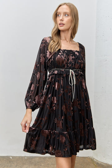 woman wearing a black floral long sleeve dress with a square neckline and tiered hem