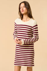 woman wearing a burgundy and cream striped sweater dress with button details on the shoulders