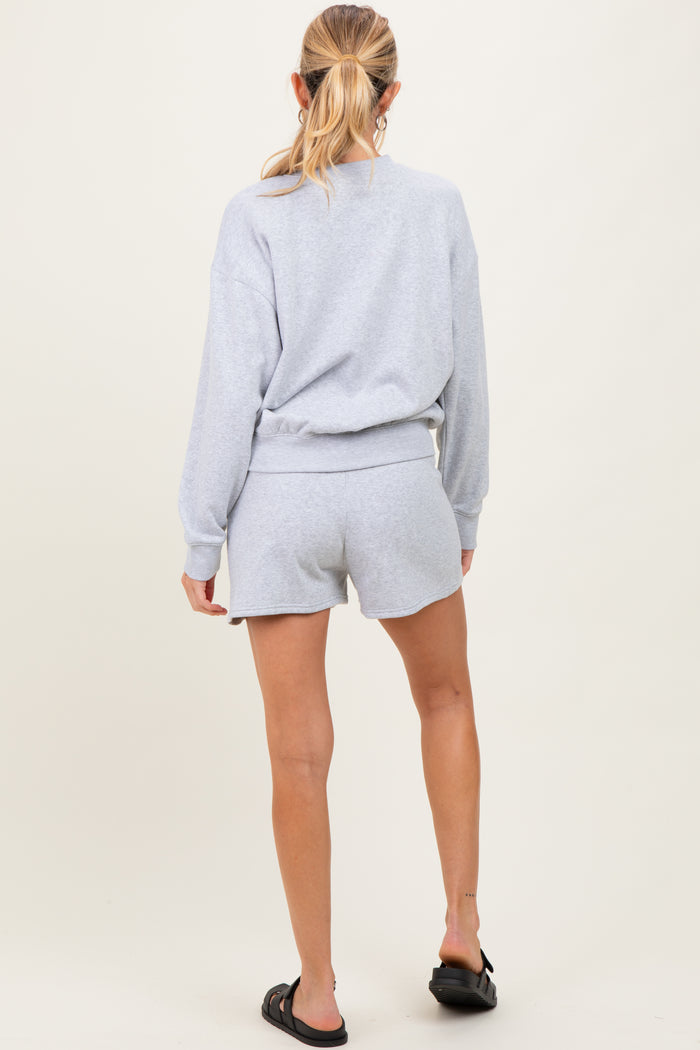 woman wearing a gray maternity sweatshirt and matching shorts, showing a casual back view