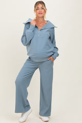 woman wearing a light blue maternity loungewear set with a hoodie and wide-leg pants, showing a baby bump