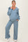woman wearing a light blue maternity loungewear set with a hoodie and wide-leg pants, showing a baby bump