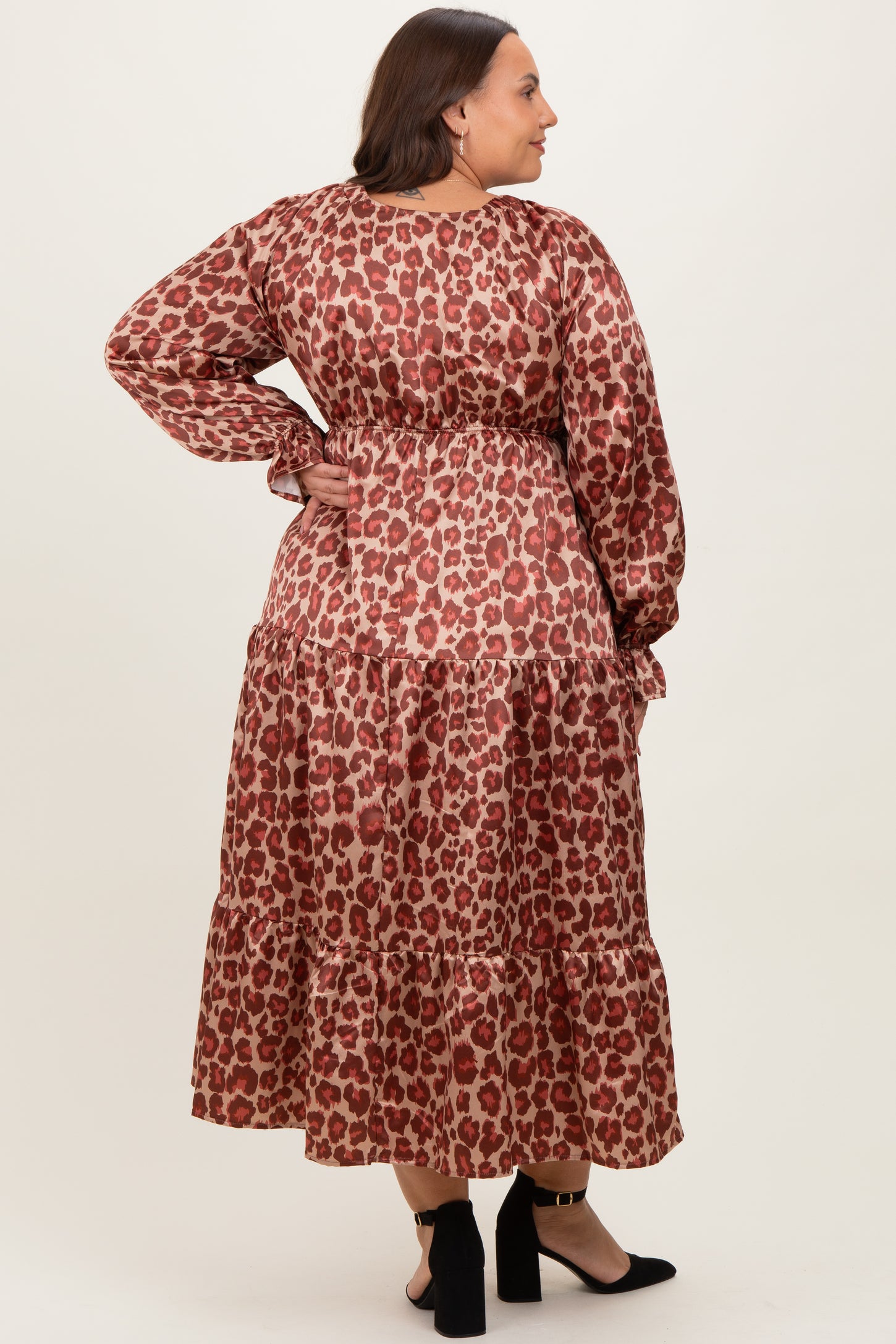 woman wearing a plus size brown leopard print maxi dress with long sleeves and a tiered skirt, facing away from the camera