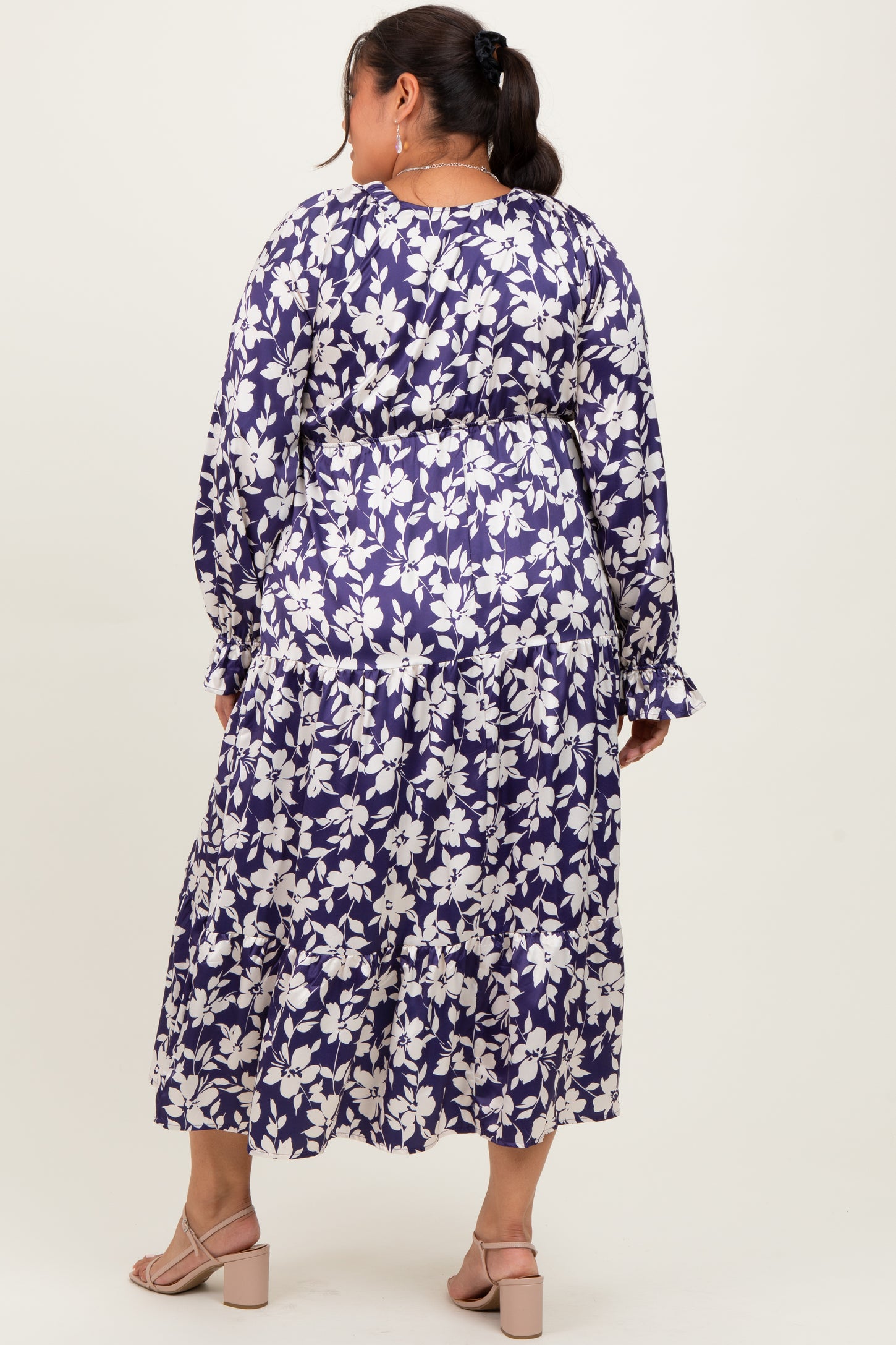 plus size woman wearing a floral purple maxi dress with long sleeves and tiered hem, viewed from the back