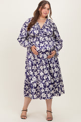 woman wearing a navy floral maternity dress with long sleeves and tiered hem, holding her baby bump
