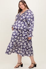woman wearing a navy blue floral maternity dress with long sleeves and a ruffled hem, showing her baby bump