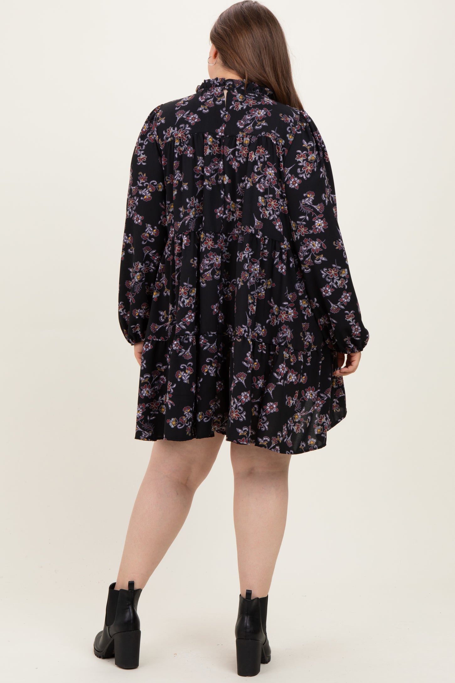 woman wearing a black floral maternity dress with long sleeves, showing a relaxed fit and ruffle collar