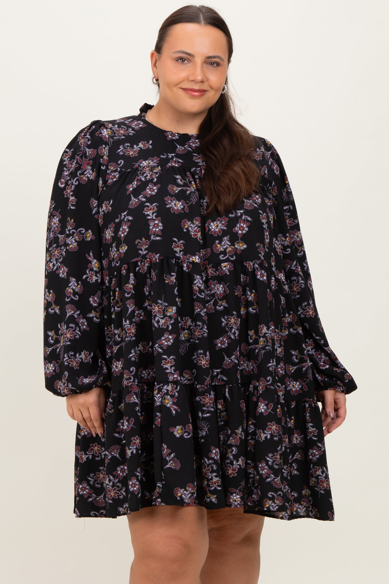 woman wearing a black floral plus size dress with long sleeves and a tiered skirt