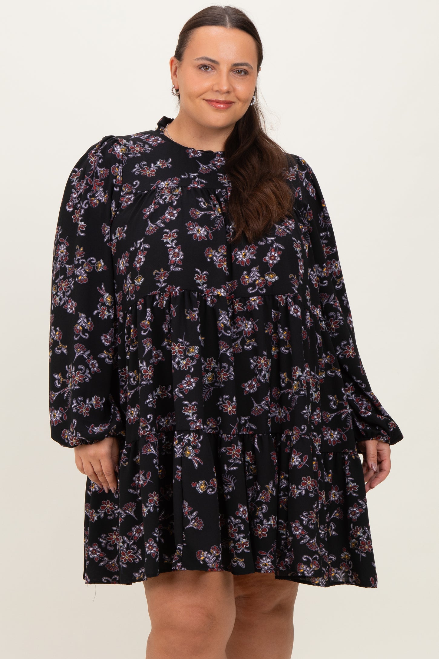 woman wearing a black floral plus size dress with long sleeves and a tiered skirt