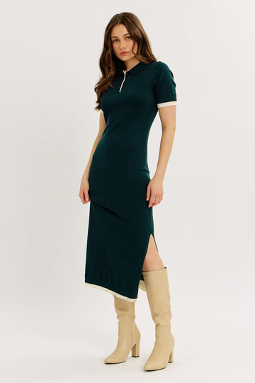 woman wearing a dark green short sleeve midi dress with a polo collar and side slits, paired with beige knee-high boots