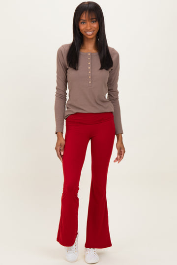 woman wearing a brown long sleeve henley top and red flared pants with white sneakers