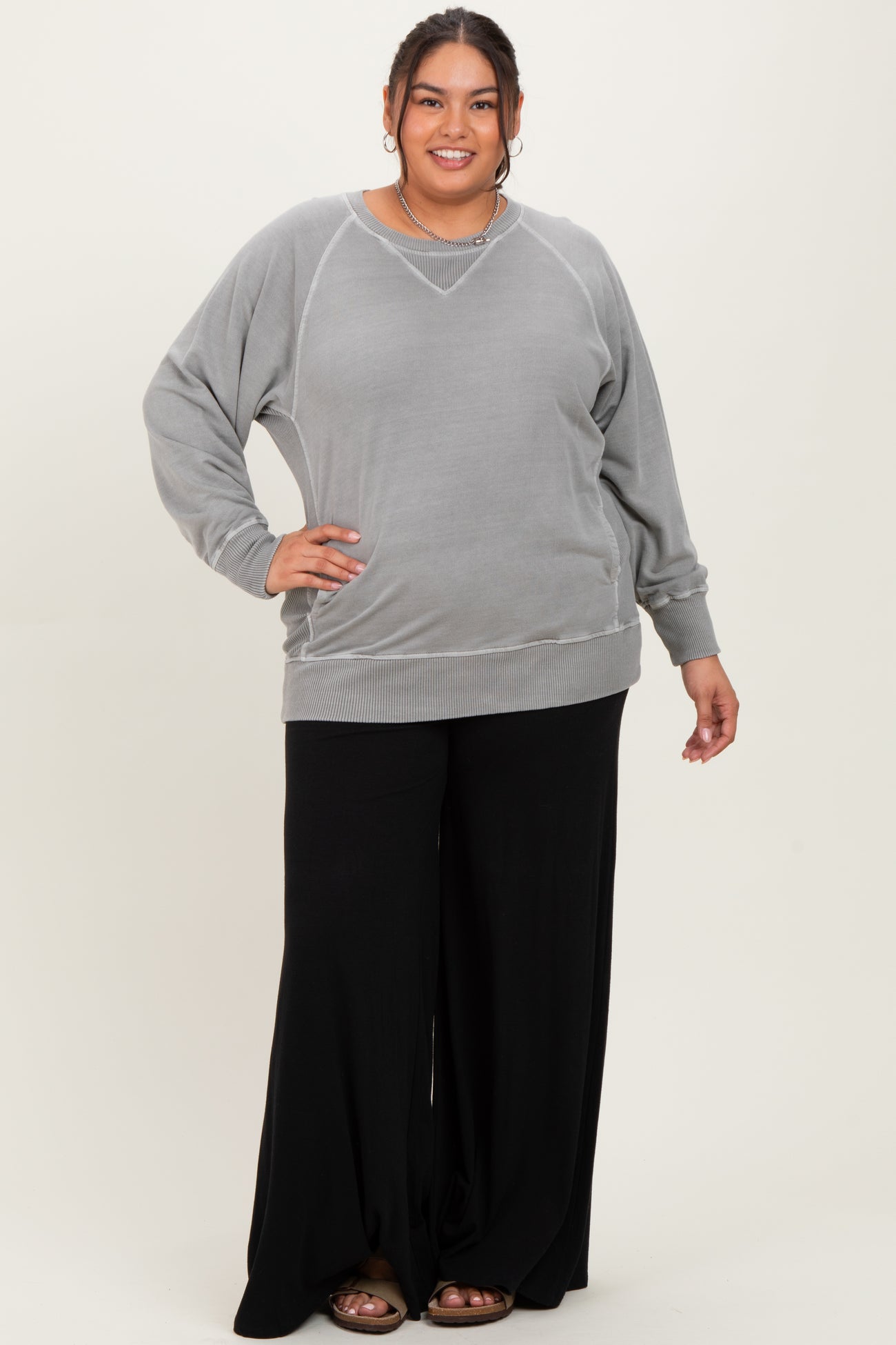 woman wearing a gray oversized sweatshirt with ribbed details and black wide-leg pants