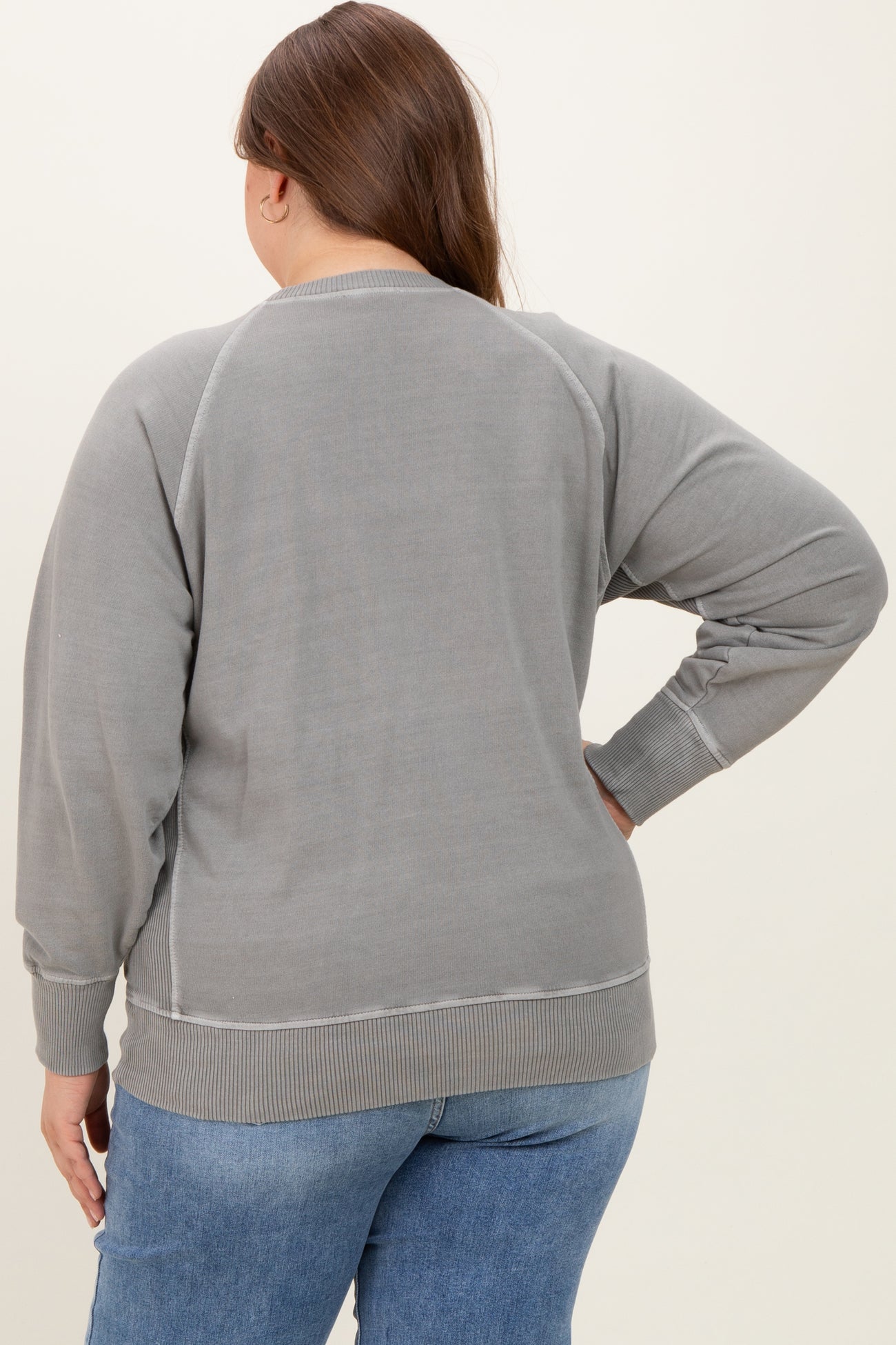 woman wearing a gray maternity plus sweatshirt with a relaxed fit, showing the back view and styled with jeans