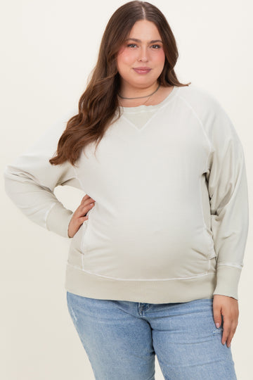 woman wearing a light beige maternity sweatshirt with a relaxed fit and a visible baby bump paired with blue jeans