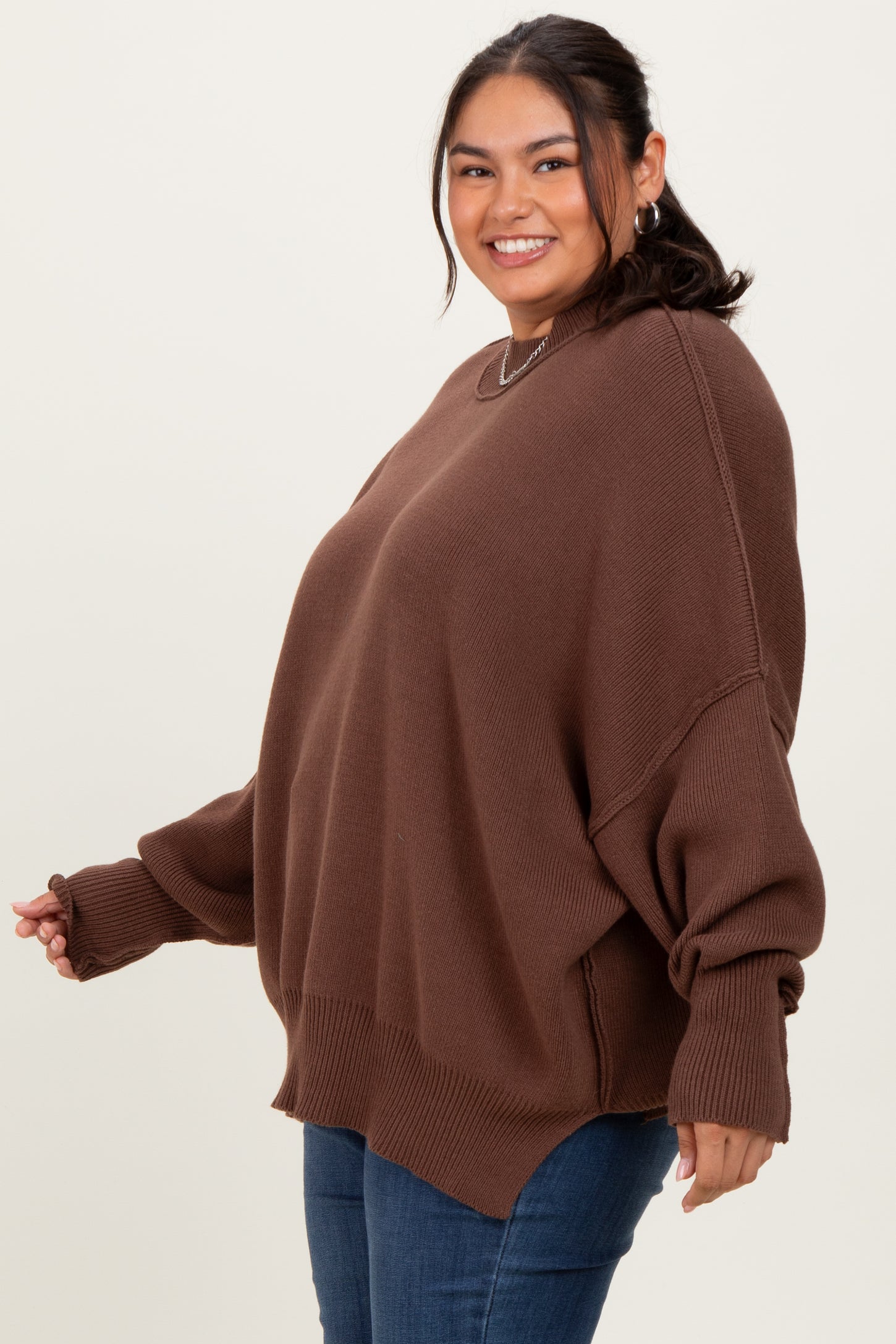 woman wearing a brown oversized sweater with long sleeves and a relaxed fit, paired with blue jeans