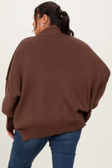 woman wearing a brown oversized knit sweater with a high neckline and relaxed fit, styled with blue jeans