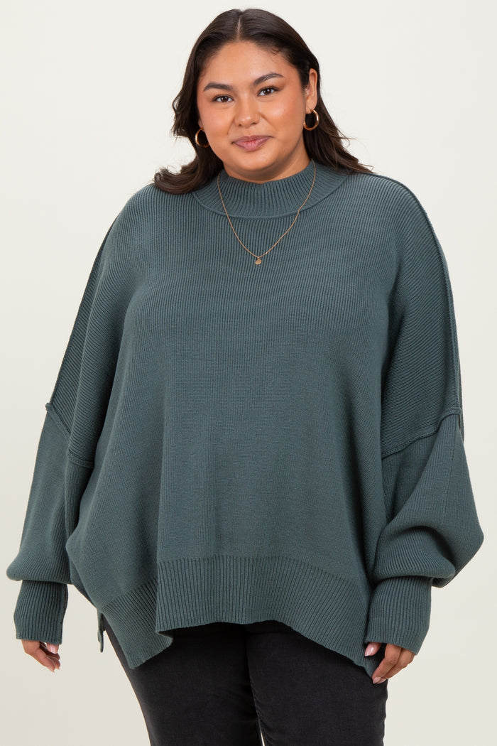 woman wearing a green oversized ribbed sweater with balloon sleeves and a high neckline, paired with black jeans
