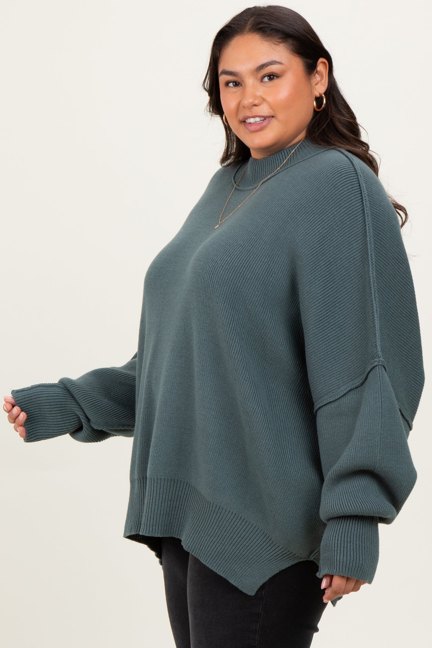 woman wearing a dark green oversized knit sweater with dropped shoulders and long sleeves