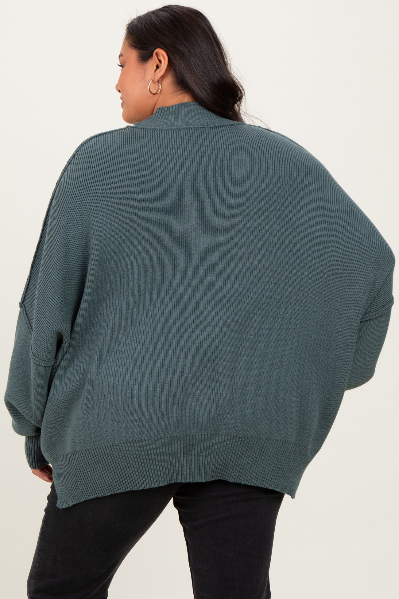 woman wearing a green oversized ribbed sweater, seen from the back, with relaxed fit and dropped shoulders