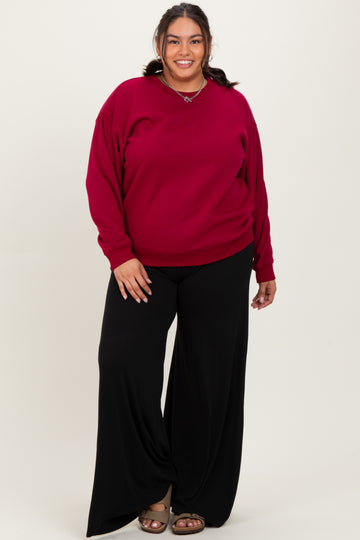 woman wearing a wine red oversized sweatshirt paired with black wide-leg pants and sandals