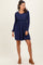 woman wearing a navy long sleeve dress with a fitted bodice and flared skirt, paired with brown heeled mules