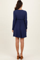 woman wearing a navy blue long sleeve dress with a flared skirt and a cinched waist, seen from the back