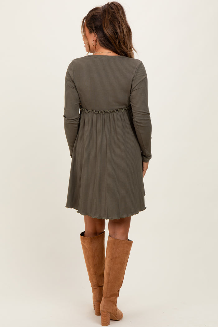 woman wearing a dark green long sleeve maternity dress with a fitted bodice and flared skirt, showing a baby bump