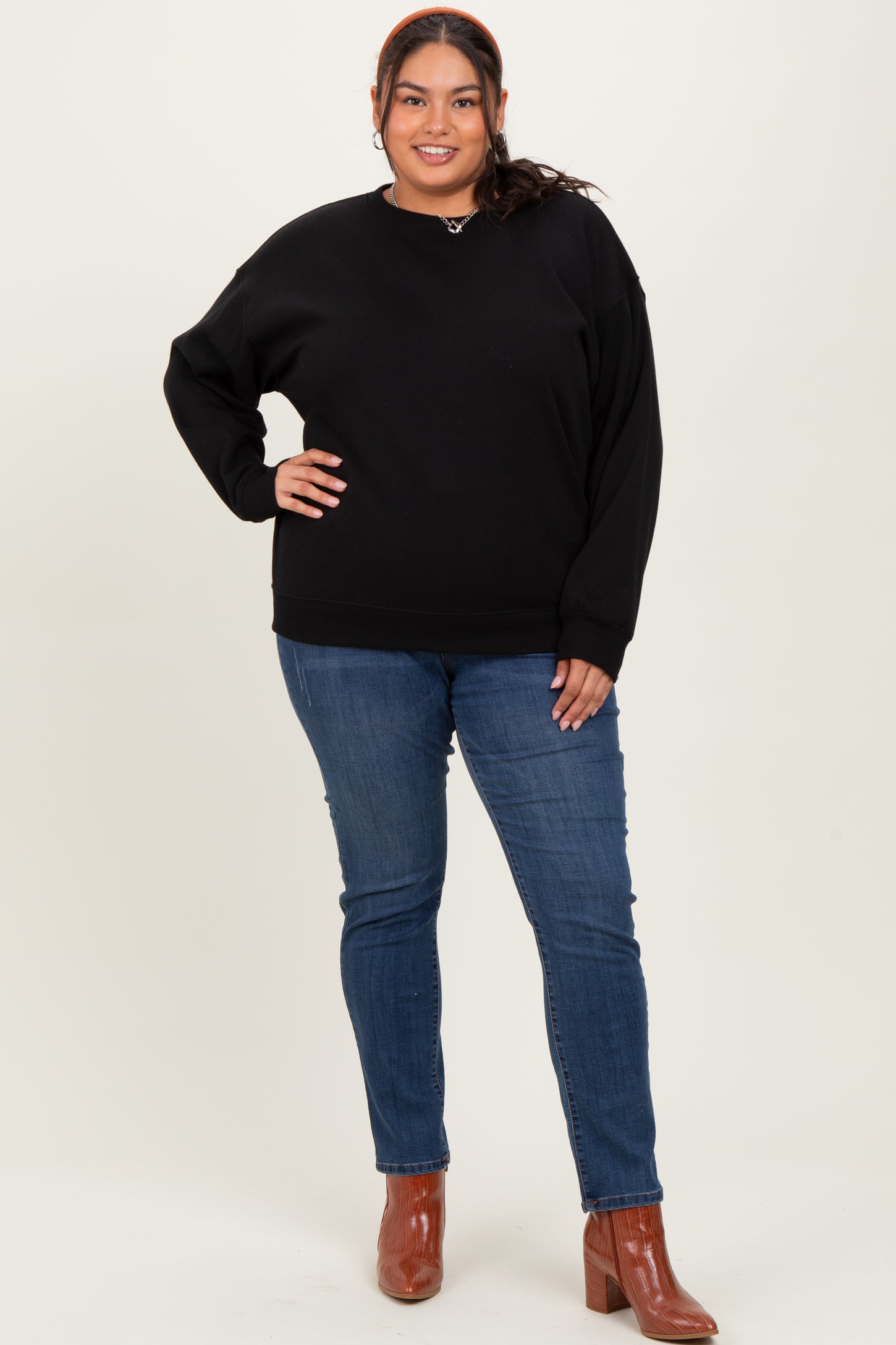 woman wearing a black oversized sweatshirt and blue skinny jeans with brown heeled boots