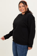 woman wearing a black oversized sweatshirt with long sleeves and a relaxed fit, paired with blue jeans
