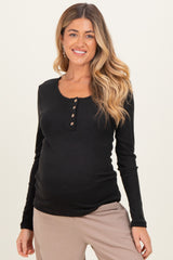 woman wearing a black long sleeve maternity top with button details and a visible baby bump