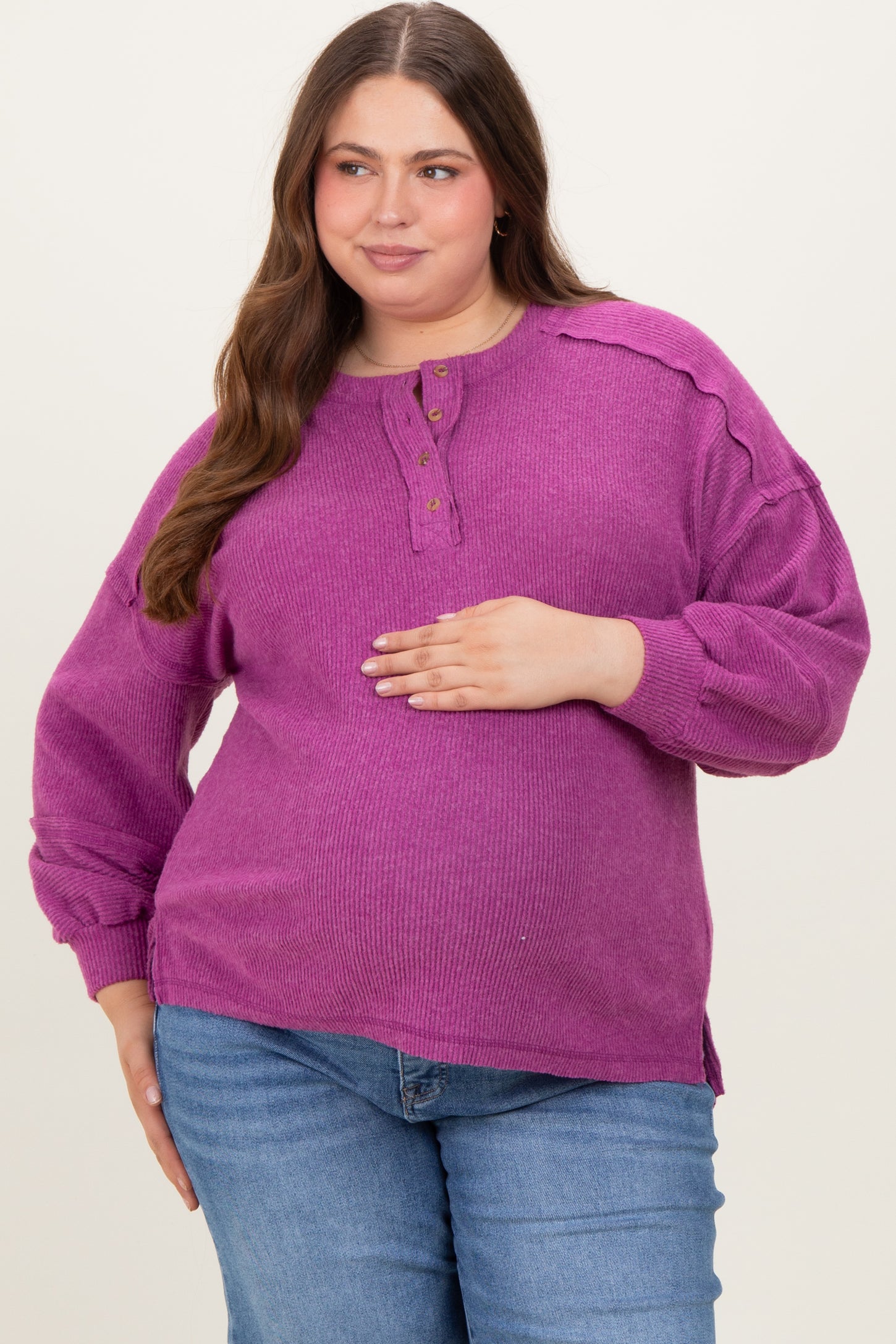 woman wearing a purple ribbed maternity plus sweater with button details and a visible baby bump