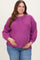 woman wearing a fuchsia maternity plus sweater with button details and a baby bump, paired with blue jeans
