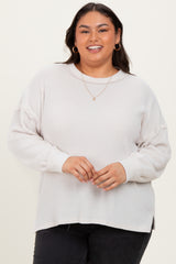 woman wearing a light gray ribbed long sleeve plus size sweater with a relaxed fit and side slits, smiling at the camera