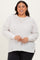 woman wearing a light gray ribbed long sleeve plus size sweater with a relaxed fit and side slits, smiling at the camera
