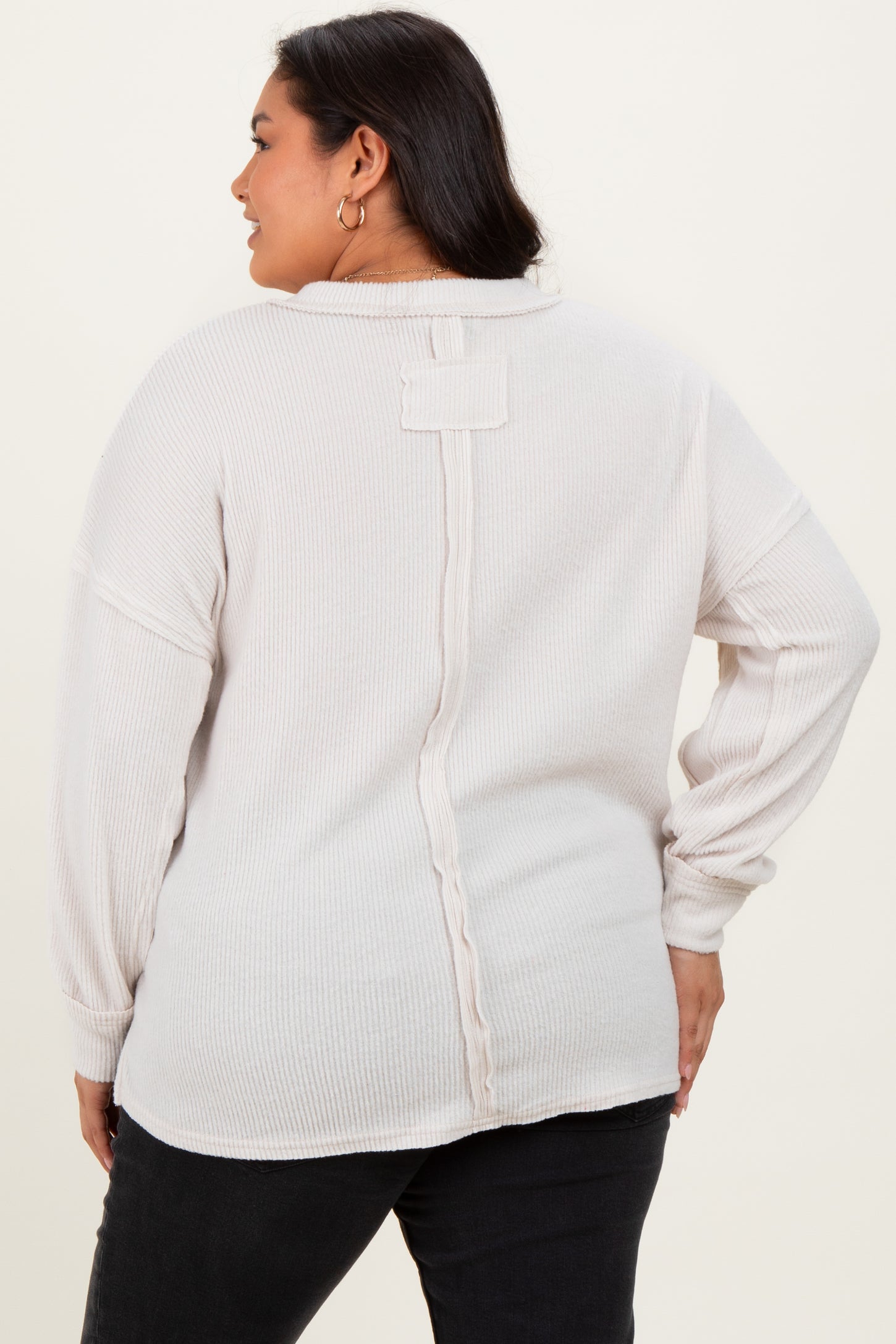 woman wearing a light beige plus size long sleeve top with a back button detail and relaxed fit