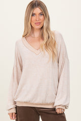 woman wearing a light beige oversized v-neck sweater with balloon sleeves and ribbed hem