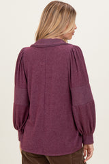 woman wearing a purple long sleeve sweater with puffed sleeves and a collar, viewed from the back