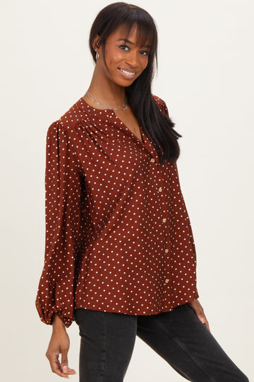 woman wearing a brown polka dot button-up blouse with long sleeves and a relaxed fit