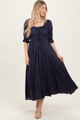 woman wearing a navy blue smocked maxi dress with puff sleeves and a drawstring waist
