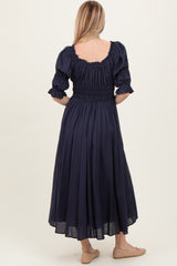 woman wearing a navy blue puff sleeve maxi dress with a smocked bodice, seen from the back