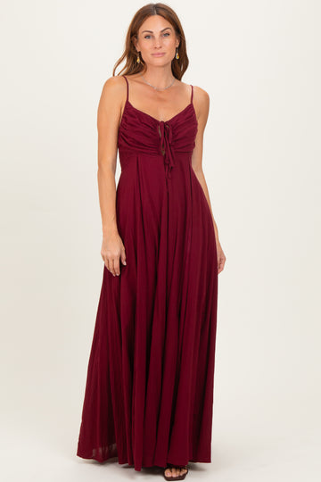 woman wearing a burgundy maxi dress with spaghetti straps and a tie detail at the chest