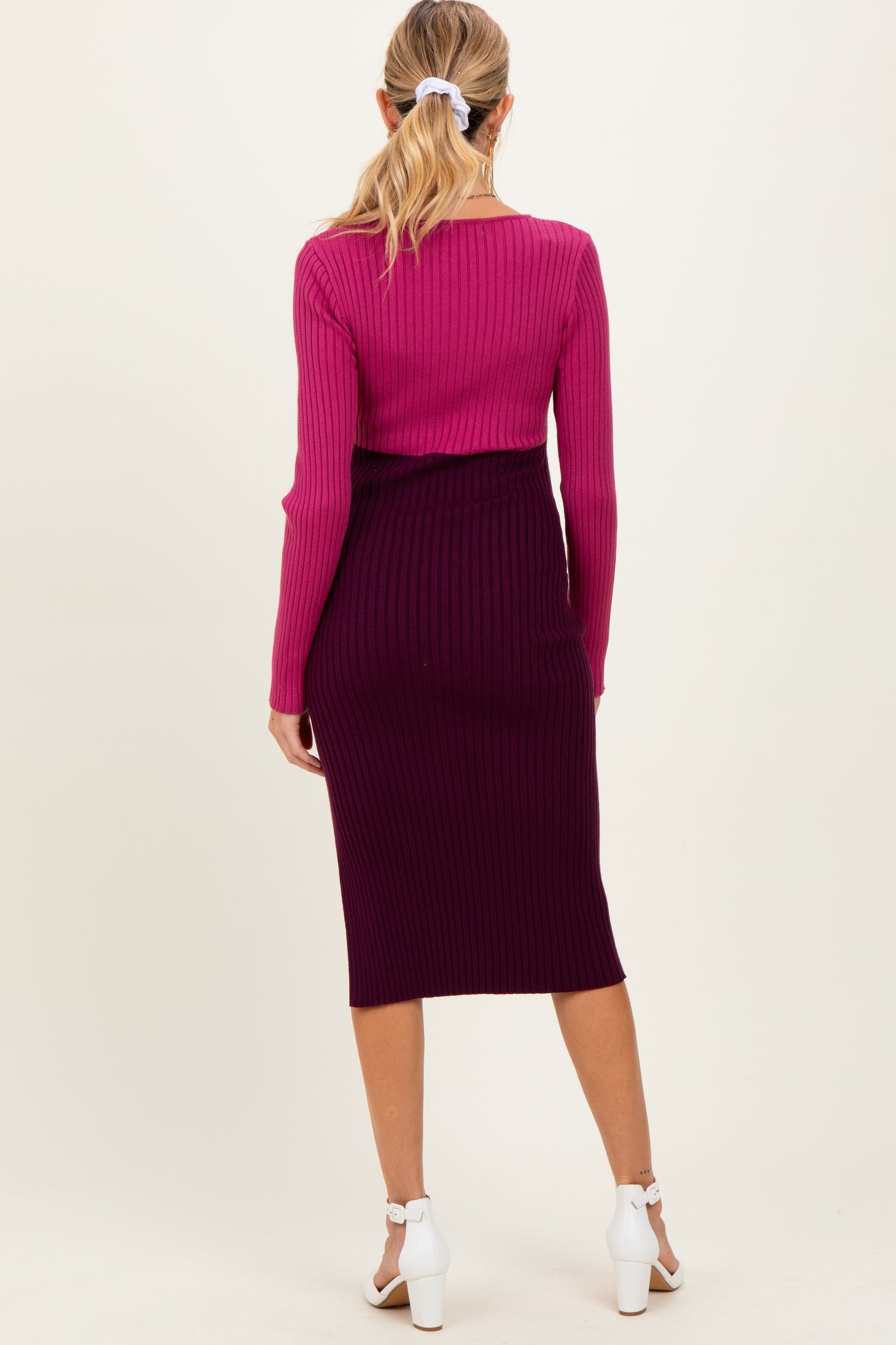 woman wearing a pink ribbed maternity top and a dark purple ribbed maternity skirt, showing a stylish layered look from the back