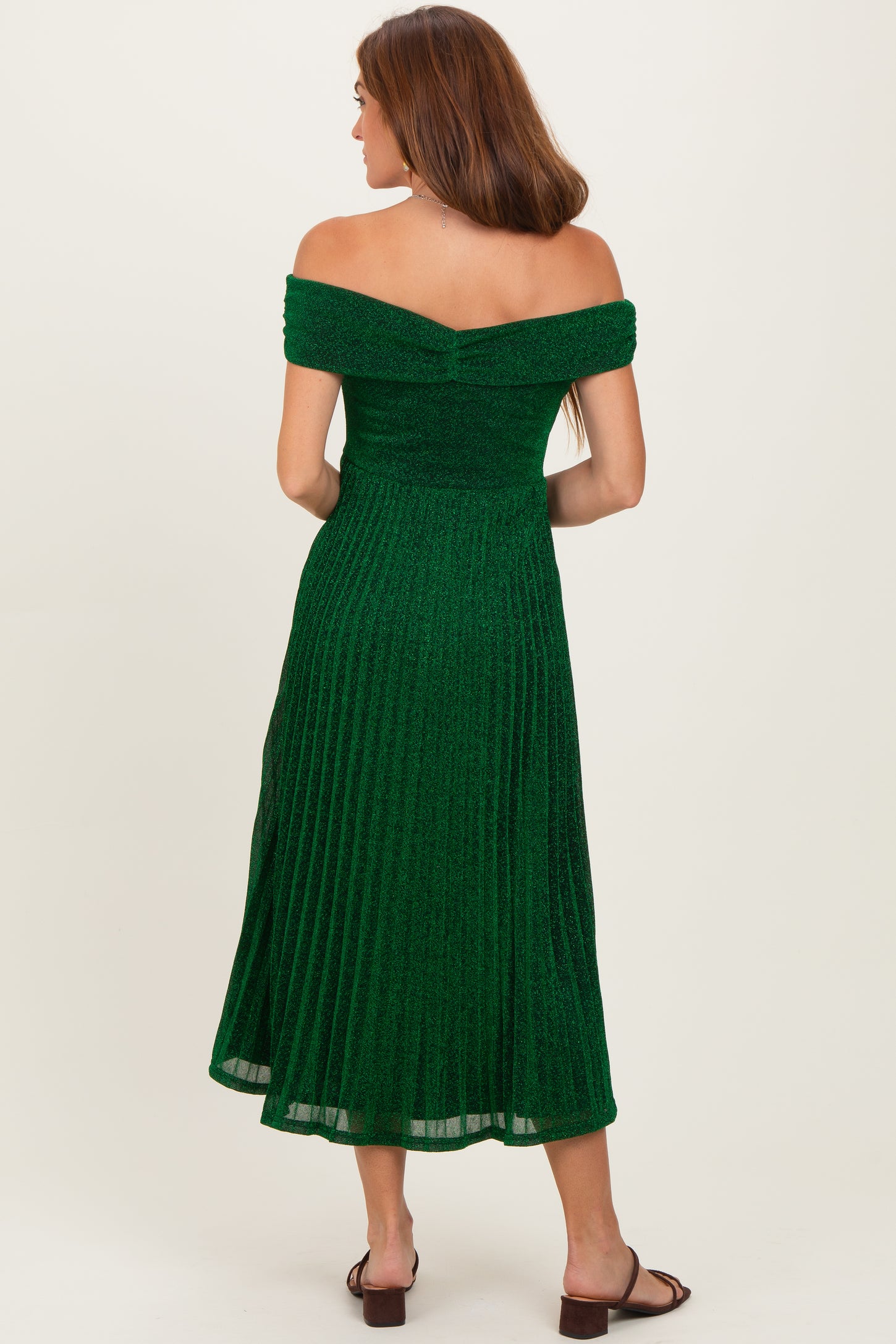 woman wearing a green off-the-shoulder pleated midi dress with a fitted bodice and flared skirt