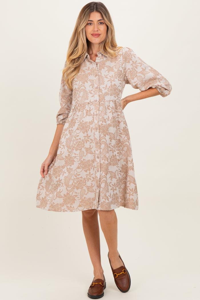 woman wearing a beige floral print maternity dress with a button-down front and three-quarter sleeves