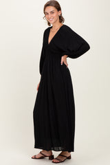 woman wearing a black maxi dress with a deep v-neck and puff sleeves, standing sideways with a flowing skirt