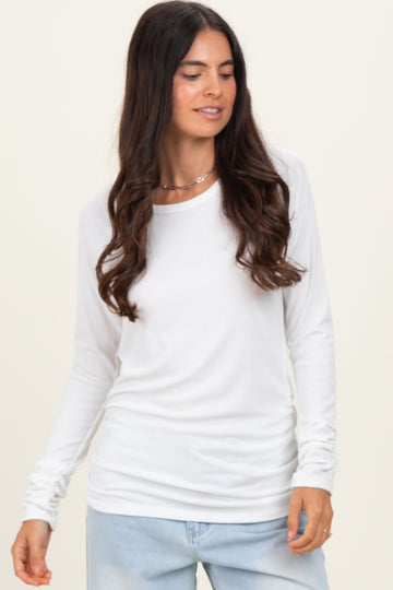 woman wearing a white long sleeve top with a relaxed fit and scoop neckline, styled with light blue jeans