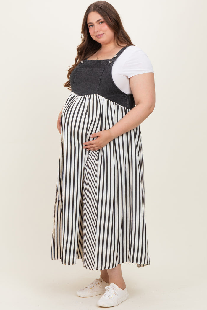 woman wearing a maternity plus striped overall dress with a denim top and a flowing skirt, holding her baby bump